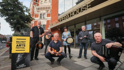 Dervish launch Belfast International Arts Festival 2021 programme. Members of the folk band are posing with their musical instruments outside Grand Opera House, Belfast.