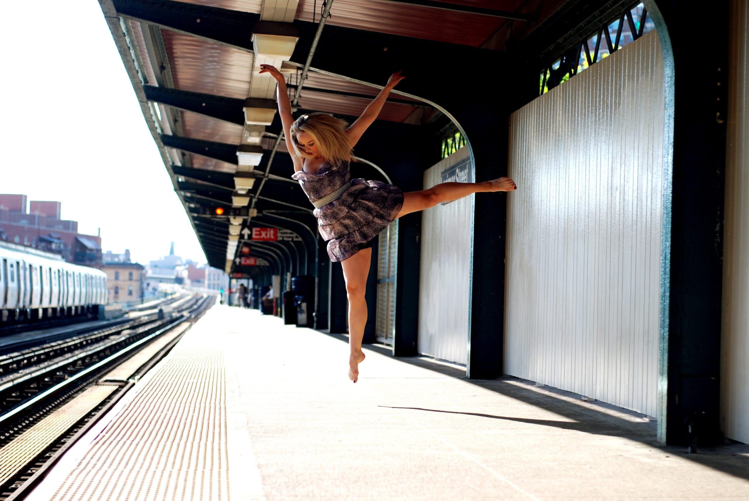 Dancer Eileen McClory in a graceful outstretched jump pose, taken on an empty train platform. Photo Credit Molly Craycroft