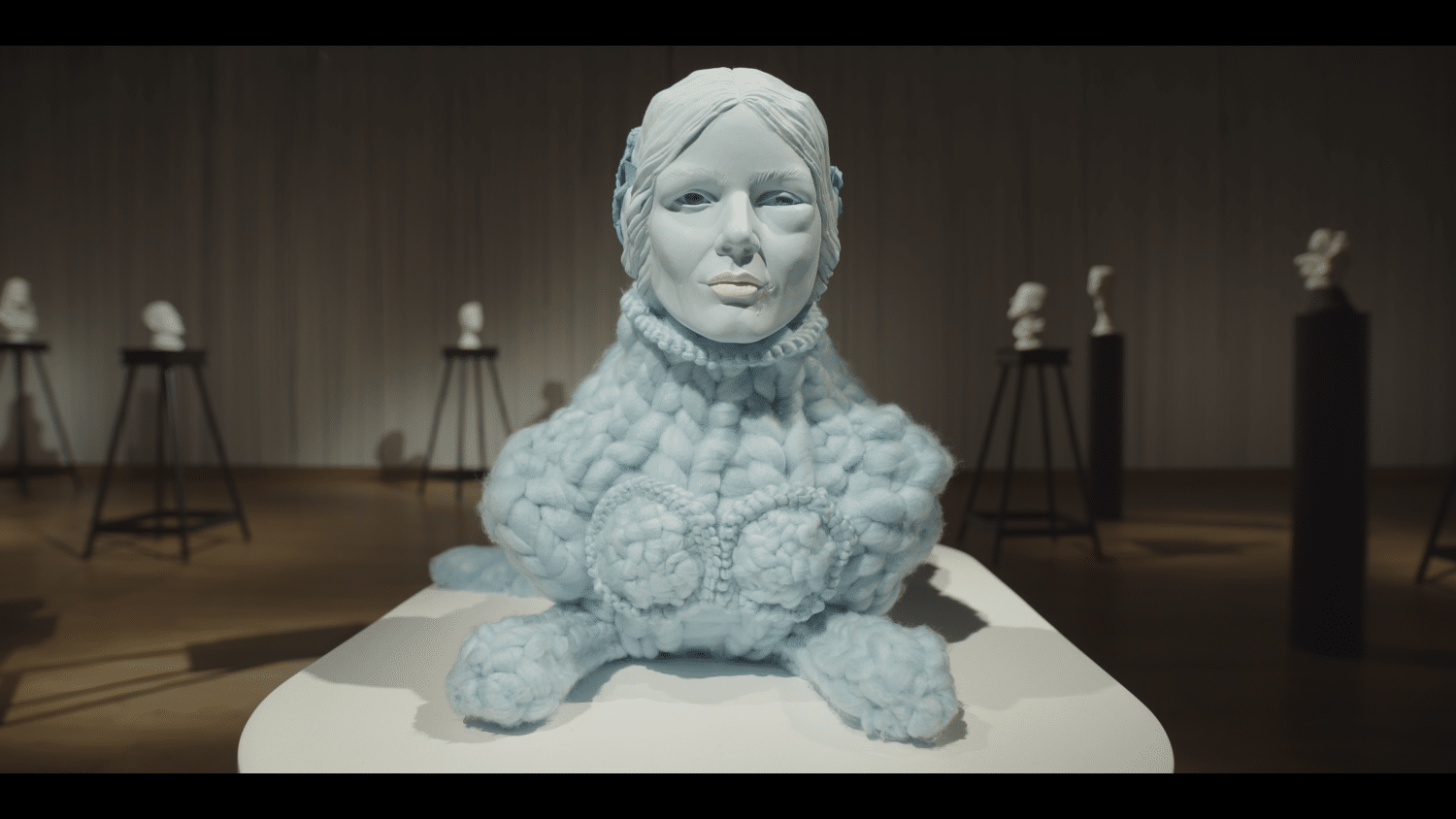 Sculpture of a bust of a woman, with a patterned knitted woollen collar. Made by Ursula Burke. Backdrop to Madrigals At The Museum performance